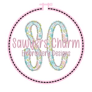 Puede incluir: Un logotipo de "Sawyers Charm Embroidery Designs" presenta un bastidor de bordado rosa con un borde punteado negro. Dentro, el n&uacute;mero "30" est&aacute; relleno con un patr&oacute;n floral. Tambi&eacute;n est&aacute; presente el texto "Sawyers Charm" y "Embroidery Designs".