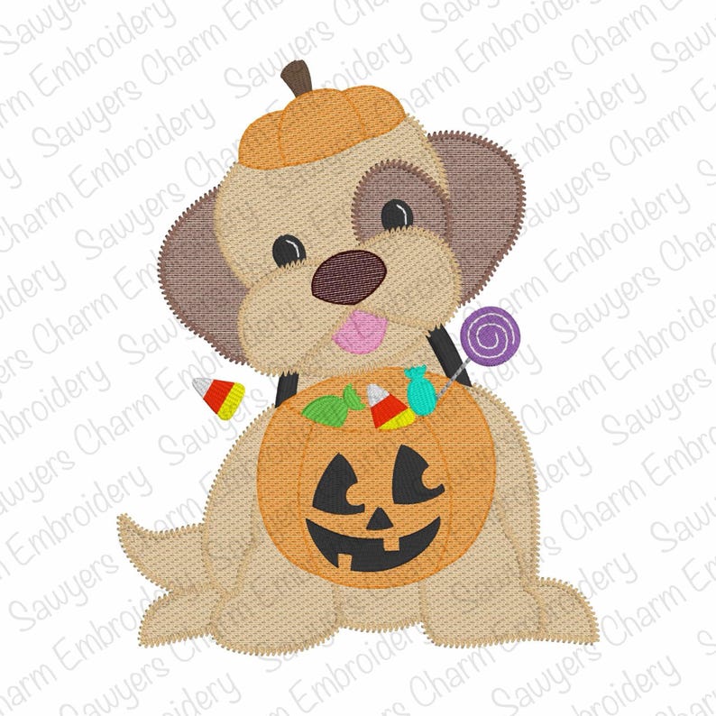 Puede incluir: Un dise&ntilde;o bordado de Halloween con un perro marr&oacute;n claro que lleva un sombrero de calabaza y lleva un cubo de jack-o'-lantern lleno de caramelos. Un chupete morado se sostiene en su boca. El perro tiene orejas marrones y una lengua rosa.