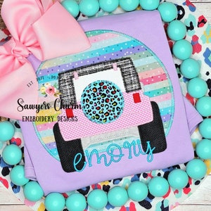 May include: Purple shirt with a pink and black jeep applique with a leopard print tire. The shirt has a colorful striped background and the name "emory" is embroidered below the jeep.