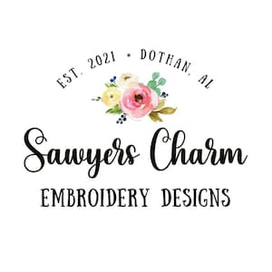 May include: A white background with the text "Sawyers Charm EMBROIDERY DESIGNS". Above the text is a floral design with pink, yellow, and blue flowers. The text "EST. 2021 DOTHAN, AL" is arched above the floral design.