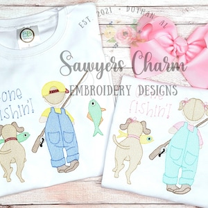 May include: Two white t-shirts with embroidery designs of children fishing. The boy's shirt says "Gone fishin!" and the girl's shirt says "Gone fishin!" Both designs feature a child holding a fishing rod with a dog and a fish.