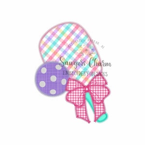 May include: A pink and green paddleball with a purple and white polka dot ball and a pink and white gingham bow. The paddleball has the text "Sawyers Charm Embroidery Designs" and "Est. 2021 Dothan, AL" on it.