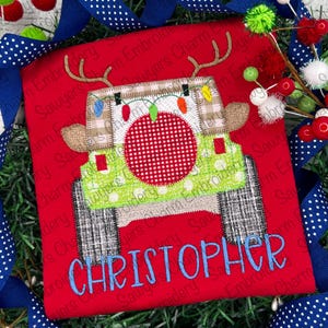 Puede incluir: Aplique navideño rojo y verde de un Jeep con cuernos de reno, luces y techo a cuadros. El nombre "CHRISTOPHER" está bordado debajo del Jeep.