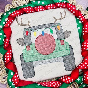 May include: A green Jeep with a red ornament on the back, decorated with Christmas lights. The Jeep has reindeer antlers on the roof.