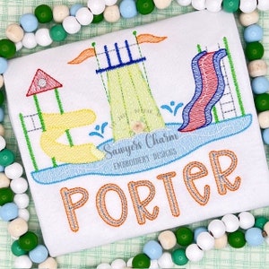 May include: White t-shirt with an embroidered water park design. The design features a yellow and red water slide, a blue pool, and the name "PORTER" in orange thread. The shirt is surrounded by colorful beads.
