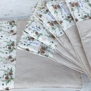 Può includere: Set di sei tovagliette all'americana in lino beige con un motivo floreale e il testo "Sugar & Honey" su ciascuna. Le tovagliette sono piegate a ventaglio.