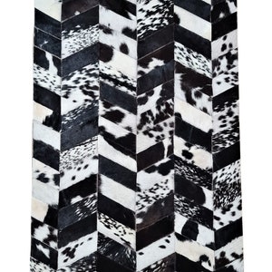 Könnte beinhalten: Schwarz-weißer Kuhfellteppich mit Chevron-Muster. Der Teppich besteht aus einzelnen Stücken Kuhfell, die zusammengenäht werden, um ein geometrisches Muster zu erzeugen.