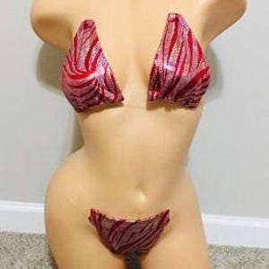 May include: A red and pink zebra print bikini top and bottom with clear straps. The bikini is made of a shiny, sparkly fabric.