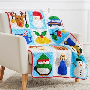 May include: A white armchair with a Christmas-themed blanket draped over it. The blanket features various holiday icons like a reindeer, Santa, and a snowman, all in a pixelated design. A small Christmas tree is to the left.