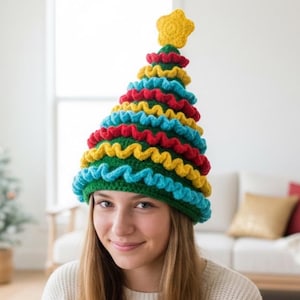 Puede incluir: Un gorro de árbol de Navidad de ganchillo hecho a mano con una estrella amarilla en la parte superior. El gorro presenta capas de verde, azul, rojo y amarillo, creando un diseño festivo y caprichoso. Perfecto para celebraciones navideñas.