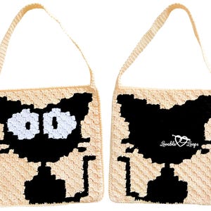 May include: A cream-colored, crocheted tote bag featuring a black cat design. The cat's face is on one side with white eyes, and the back side has a black cat silhouette with the text "Lovable Loops". The bag has a matching strap.