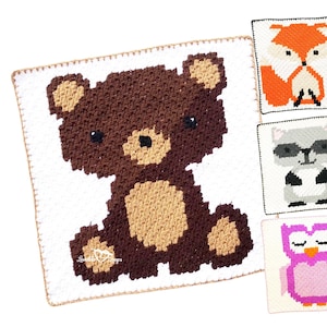 May include: A crochet blanket with a brown bear, fox, raccoon, and owl design. Each animal is in a separate square on the blanket.
