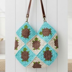 Puede incluir: Bolso tote de crochet hecho a mano con un diseño de tortuga. El bolso presenta un patrón de patchwork de cuadrados turquesa, marrón y crema. Tiene correas de cuero marrón y herrajes metálicos.