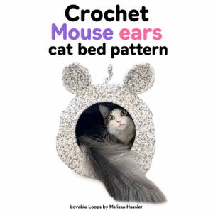May include: A speckled white and grey crochet cat bed shaped like a mouse with two rounded ears and a small tail on top. A long-haired black and white cat sits inside the opening. The text reads: Crochet Mouse ears cat bed pattern, Lovable Loops by Melissa Hassler.