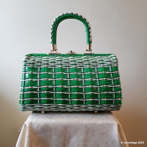 May include: A green and white woven plastic handbag with a silver handle. The bag has a rectangular shape and a woven pattern.