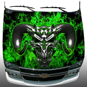May include: A vehicle hood wrap featuring a detailed, metallic skull with large horns, set against a backdrop of vibrant green flames on a black background. The wrap covers the hood of a white truck, showcasing a bold, edgy design.