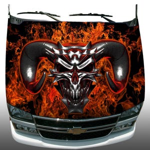 May include: A black and orange car hood wrap with a silver skull with horns and flames.