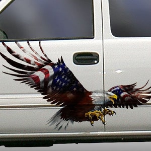 Op de afbeelding: Een witte pick-up truck met een sticker van een Amerikaanse zeearend met zijn vleugels wijd uitgespreid. De adelaar vliegt met zijn klauwen uitgestoken. De vleugels van de adelaar zijn versierd met de Amerikaanse vlag.