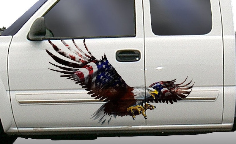 Op de afbeelding: Een witte pick-up truck met een sticker van een Amerikaanse zeearend met zijn vleugels wijd uitgespreid. De adelaar vliegt met zijn klauwen uitgestoken. De vleugels van de adelaar zijn versierd met de Amerikaanse vlag.