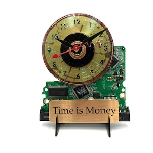 May include: A clock made from a recycled computer hard drive with a gold and black face and the words "Time is Money" on a brass plaque.