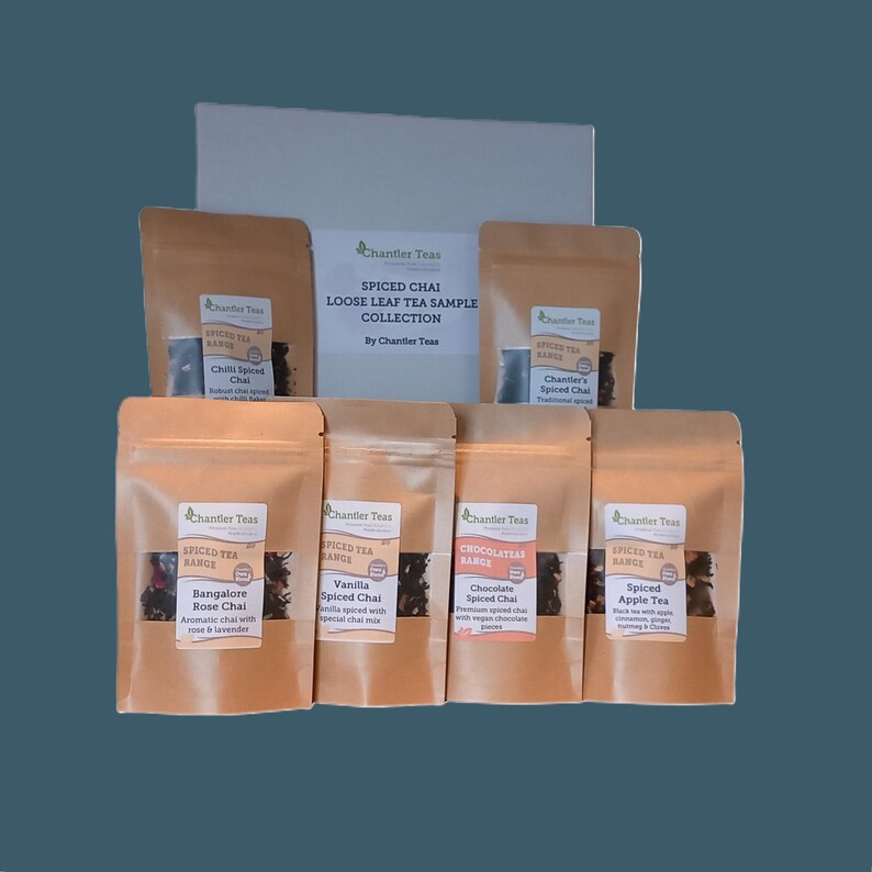 May include: A collection of six small brown paper bags containing loose leaf tea blends. The bags are labeled with the names of the tea blends: Chilli Spiced Chai, Chantler's Spiced Chai, Bangalore Rose Chai, Vanilla Spiced Chai, Chocolate Spiced Chai, and Spiced Apple Tea. The bags are arranged in a row on a white surface. The text on the bags reads "Spiced Tea Range" and "Chantler Teas".