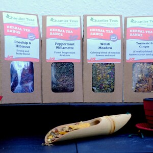 Puede incluir: Cuatro cajas de cart&oacute;n marr&oacute;n con ventanas de pl&aacute;stico transparente que muestran diferentes mezclas de infusiones de hierbas. Las cajas est&aacute;n etiquetadas con "Chantler Teas Herbal Tea Range" y enumeran los sabores de t&eacute;: Rosa mosqueta e hibisco, Menta Willamette, Prado gal&eacute;s y C&uacute;rcuma y jengibre.
