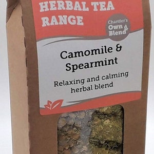 Pu&ograve; includere: Una scatola di cartone marrone con una finestra che mostra una miscela di erbe secche. La scatola ha un'etichetta che recita "Chantler Teas" e "Herbal Tea Range". L'etichetta dice anche "Camomilla & Menta" e "Miscela di erbe rilassante e calmante".
