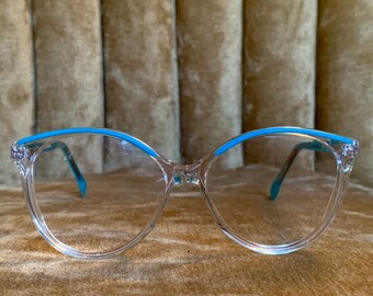May include: Clear plastic eyeglasses with a blue rim. The glasses have a cat-eye shape.