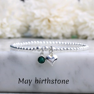 Può includere: Un braccialetto di perline d'argento con una pietra preziosa verde e un ciondolo a forma di cuore d'argento. Pietra di nascita di maggio.