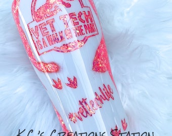 May include: White tumbler with a pink and orange glitter design. The tumbler features a pink dinosaur silhouette with the text "Vet Tech is a walk in the park" and the hashtag "#vettechlife".