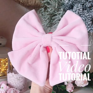 May include: A large pink velvet bow with a tutorial video overlay. The text on the overlay reads "Tutorial Video Tutorial".
