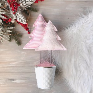 May include: Two pink Christmas tree ornaments with white stripes and white polka dots, in a white pot with pink straw.