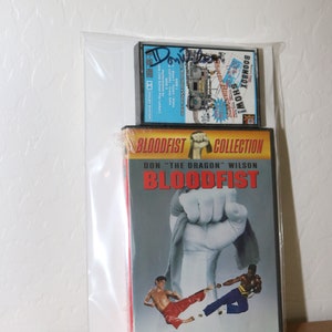 May include: A DVD case featuring the movie "Bloodfist" starring Don "The Dragon" Wilson and Billy Blanks. The case is red and black with a picture of a fist on the front. The text "Bloodfist Collection" is printed on the case.