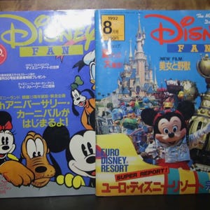Puede incluir: Dos revistas vintage de Disney Fan. La revista de la izquierda presenta a Mickey, Minnie y Goofy, con texto en japonés. La revista de la derecha tiene a Mickey Mouse frente a un castillo, con el texto "Euro Disney Resort".