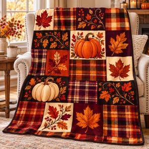 May include: A rectangular throw blanket featuring a patchwork design of autumn-themed squares. The pattern includes orange pumpkins, red and gold maple leaves, berry sprigs, and plaid blocks in shades of burgundy, orange, yellow, and brown.