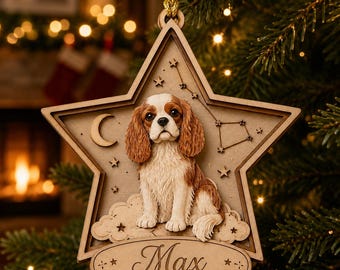 Puede incluir: Un adorno de madera en forma de estrella con un Cavalier King Charles Spaniel tridimensional sentado sobre una nube. El diseño incluye una luna creciente, estrellas pequeñas y una constelación. El nombre Max está grabado en una cinta.