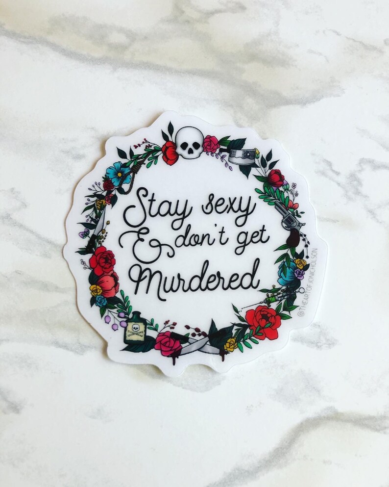 May include: A white sticker with a floral wreath design. The wreath includes a skull, a gun, a knife, a syringe, and a bottle of poison. The text inside the wreath reads "Stay sexy & don't get murdered".