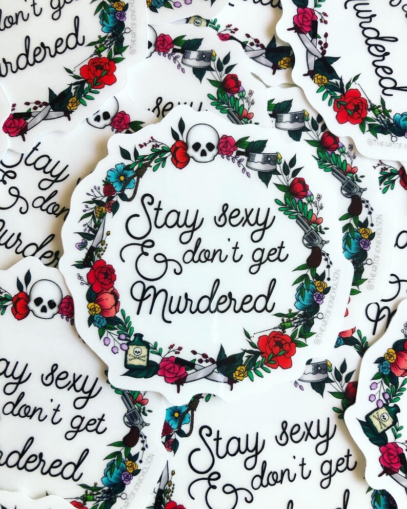 May include: A white sticker with a floral wreath design. The wreath includes a skull, a gun, a knife, a bottle of poison, and a noose. The text inside the wreath reads "Stay sexy & don't get murdered".