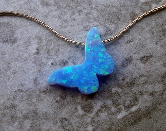 May include: A delicate silver chain necklace with a blue opal butterfly pendant. The butterfly is iridescent and has a light blue color with hints of green and purple.