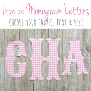 May include: Iron on monogram letters featuring the letters G, H, and A in a pink and white gingham check pattern. The text Iron on Monogram Letters and CHOOSE YOUR FABRIC, FONT & SIZE is displayed at the top of the image in pink and black.