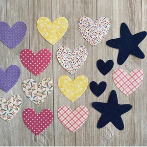 May include: A collection of assorted fabric cutouts including multiple heart shapes and two star shapes. The hearts feature various patterns such as polka dots, floral prints, and gingham checks in colors like purple, yellow, pink, and white. Two dark navy blue stars are included.