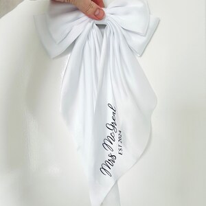 May include: White satin bow with a long tail, featuring the text "Mrs. McGreat EST 2024" in black script.