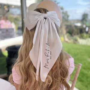 May include: White satin hair scarf with a large bow and the text "Mrs. Roberts Est 2023" printed in black.
