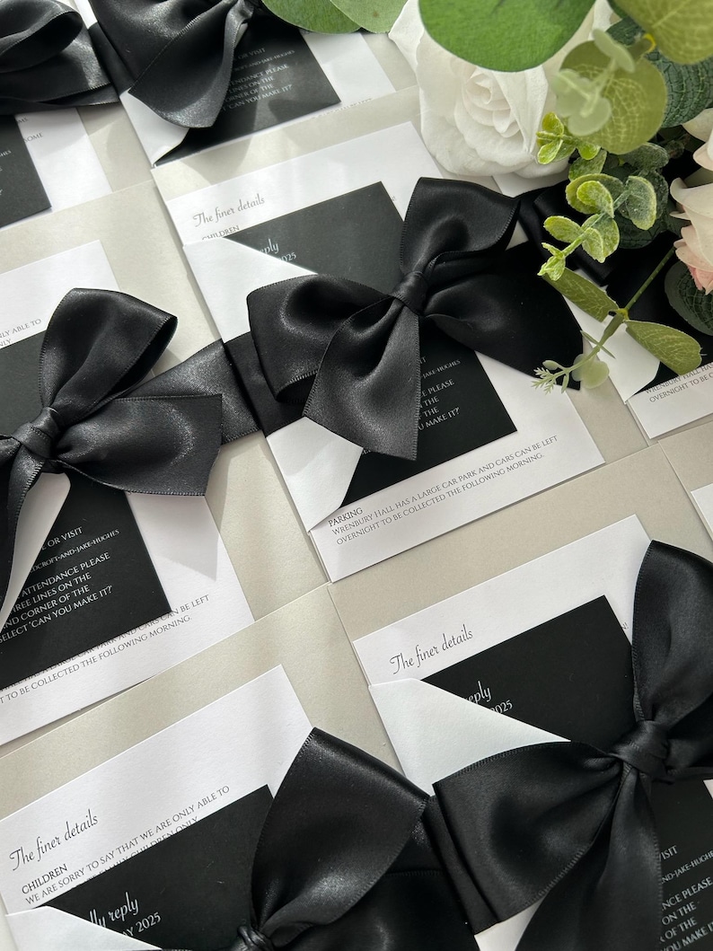 Pode incluir: Cart&otilde;es de convite de casamento preto e branco com la&ccedil;os de cetim preto. O texto nos cart&otilde;es diz "Os detalhes mais finos" e inclui informa&ccedil;&otilde;es sobre estacionamento, crian&ccedil;as e detalhes de resposta.
