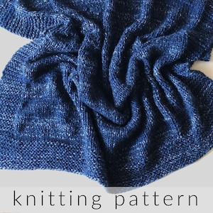 Può includere: Una coperta di maglia blu con un motivo maculato. La coperta è piegata e drappeggiata su una superficie bianca. Il testo "knitting pattern" è stampato sotto la coperta.