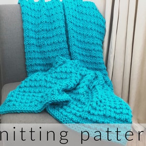 May include: A bright turquoise hand-knitted blanket featuring a textured waffle stitch pattern. The thick yarn creates a raised grid design across the entire surface of the fabric. The text "knitting pattern" is printed in black at the bottom.