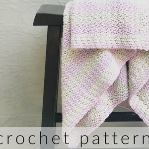 May include: A crocheted blanket in shades of pink and white, draped over a black wooden stool. The blanket has a textured, stitch-like pattern.
