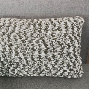 May include: A grey and white knitted cushion with a textured pattern.