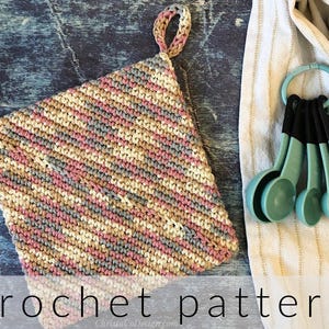 May include: A handmade crochet potholder in a diagonal striped pattern, featuring shades of pink, gray, and beige. The potholder has a loop for hanging. Next to it are a set of turquoise measuring spoons.