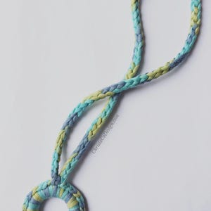 May include: A blue, green, and yellow braided cord necklace with a matching crocheted ring pendant.